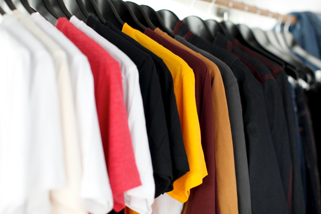Assorted blank T-shirts in multiple colors hanging on a clothing rack, ideal for custom printing, team apparel, promotional merchandise, and branded clothing.