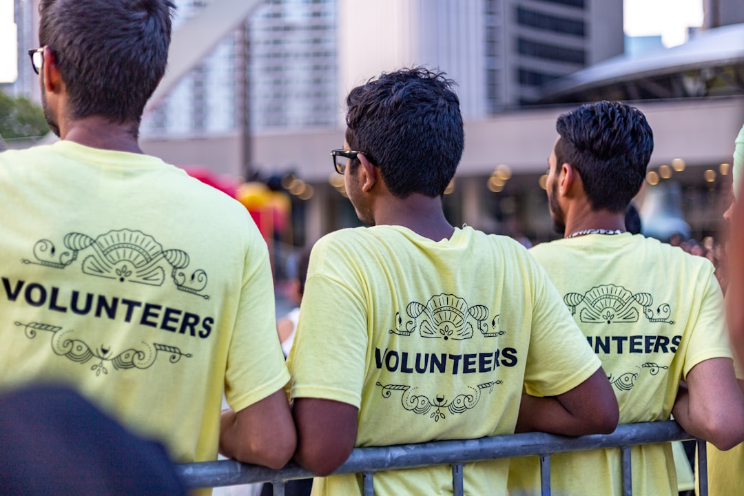 Custom charity event t-shirts displayed on hangers in black, white, and gray colors, featuring vibrant orange graphic designs and event branding, ideal for fundraising campaigns, community events, and nonprofit organizations.